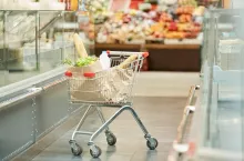 Full length background image of shopping cart with groceries standing in supermarket, copy space