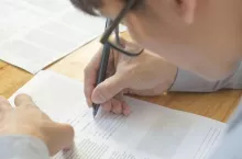 Man completing personal information on a application form. Select focus at hand and pen.