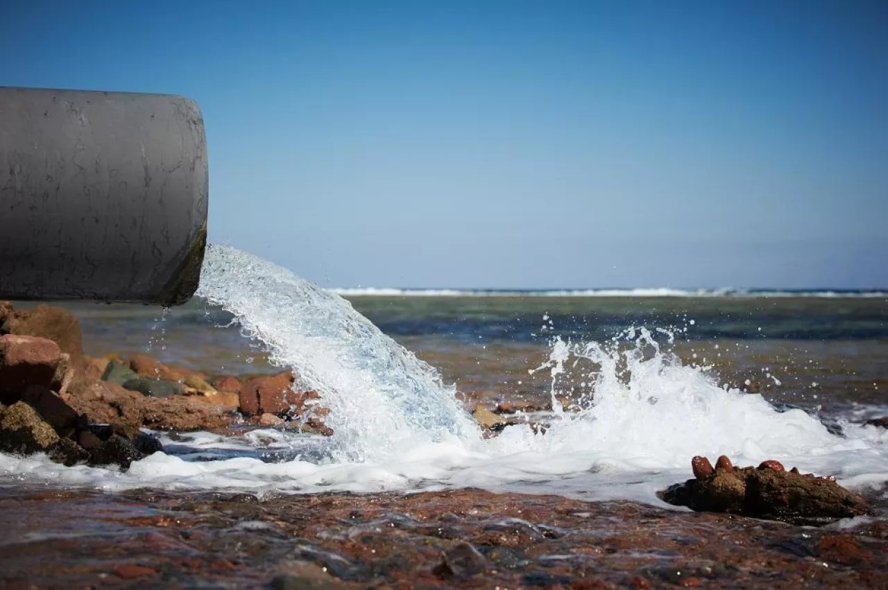 clear water flows from a pipe into the sea.