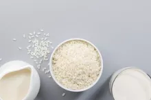 Vegan Rice milk with rice grains on gray background. Copy space, top view