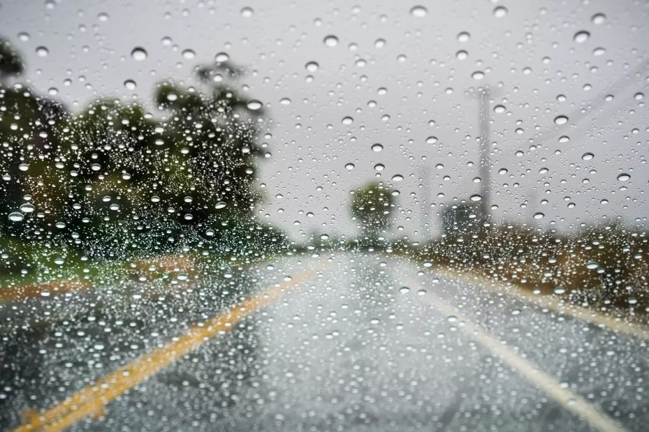Raindrops on the windshield on a rainy day; empty street in the background; California