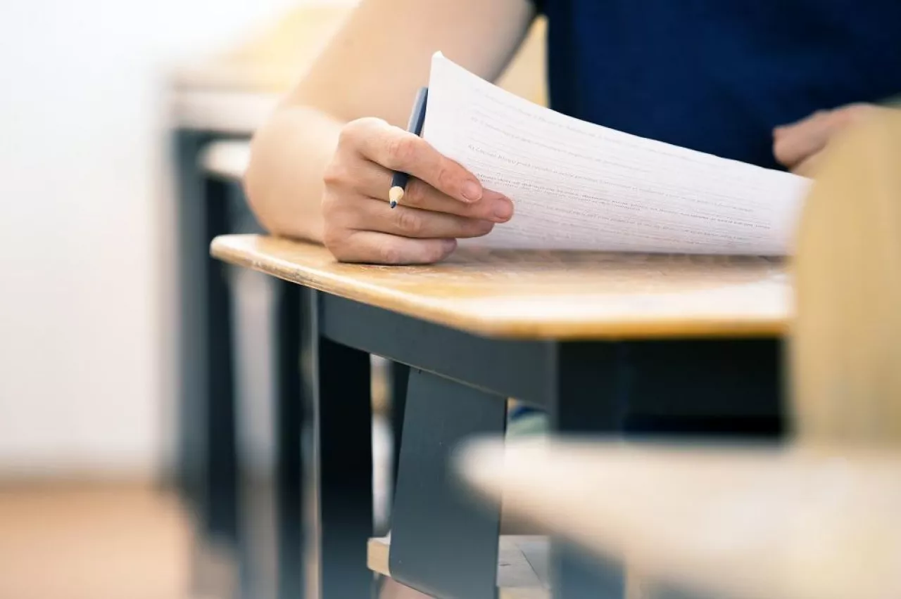 High school or university student holding pencil writing on paper answer sheet. Final exam concept.