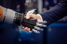 Hand of a businessman shaking hands with a Android robot. The concept of human interaction with artificial intelligence.