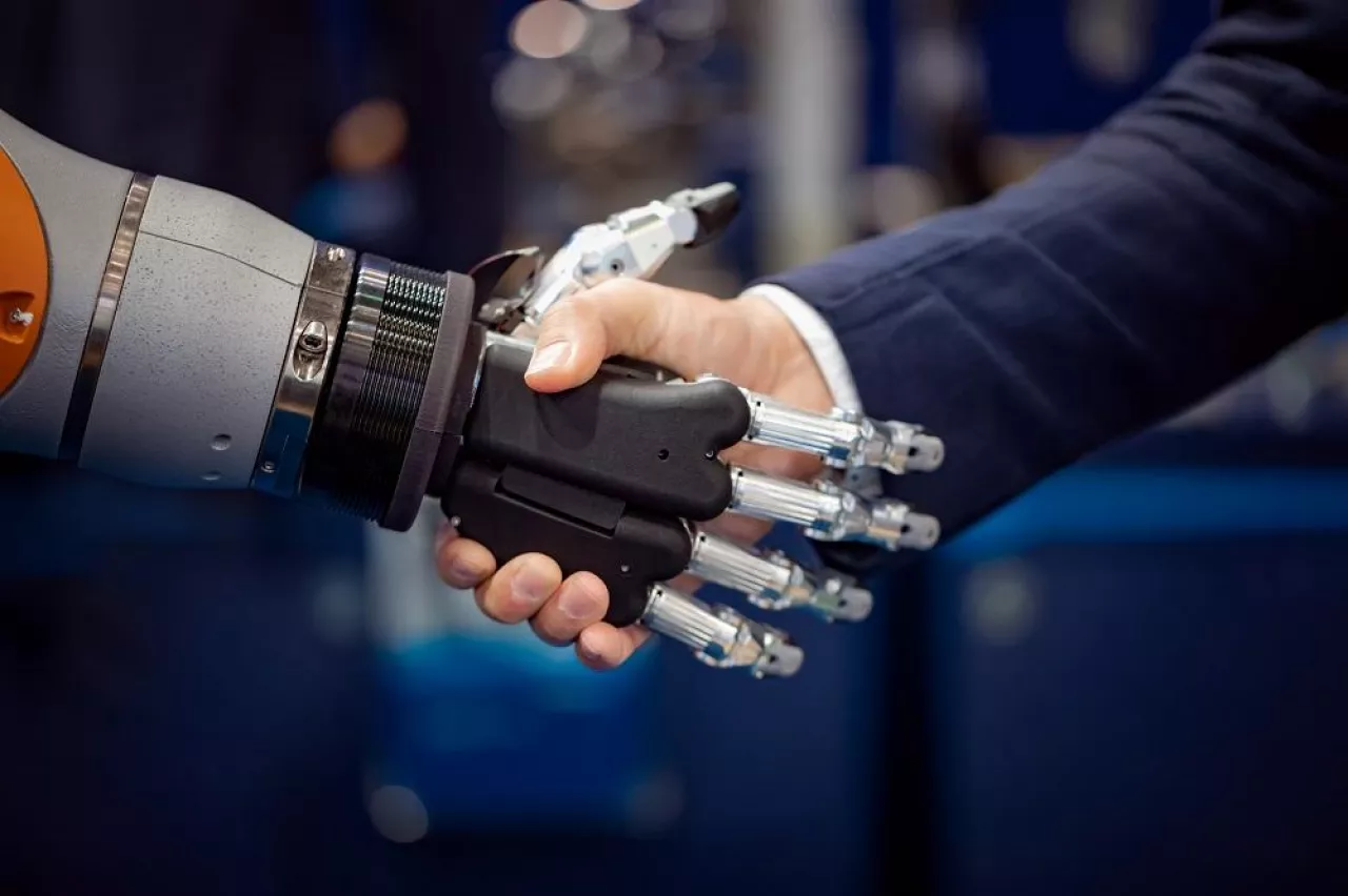 Hand of a businessman shaking hands with a Android robot. The concept of human interaction with artificial intelligence.