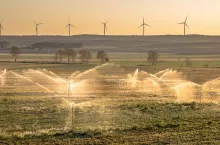 Irrigation sprinklers watering farmland at sunset in Huesca area, Spain.