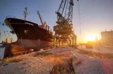 big cargo ship bulk carrier is loaded with grain of wheat in port at sunset