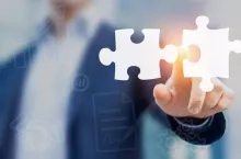 Mergers and acquisition concept with consultant touching icons of puzzle pieces representing the merging of two companies or joint venture, partnership